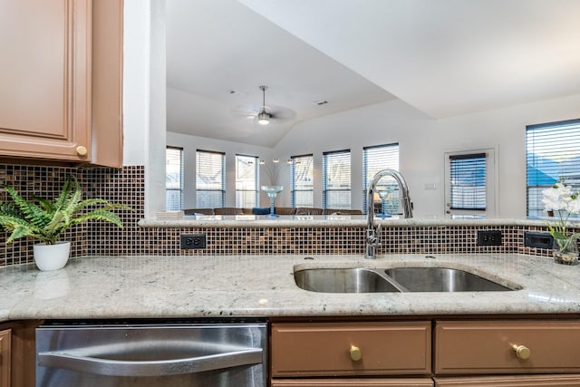 kitchen with light stone countertops, a sink, stainless steel dishwasher, and tasteful backsplash