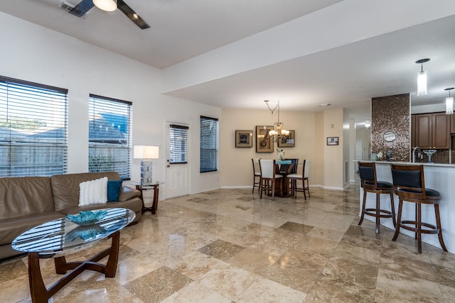 living room with baseboards, a wealth of natural light, visible vents, and ceiling fan with notable chandelier