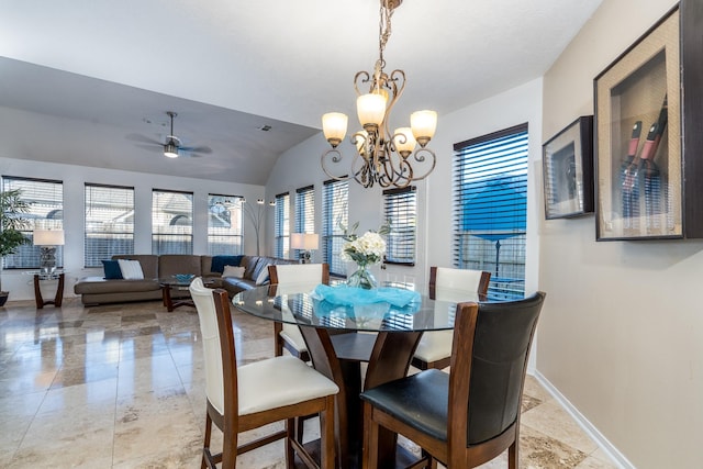 dining space with ceiling fan with notable chandelier, baseboards, and vaulted ceiling