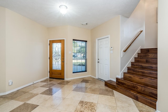 entryway featuring baseboards, visible vents, and stairway