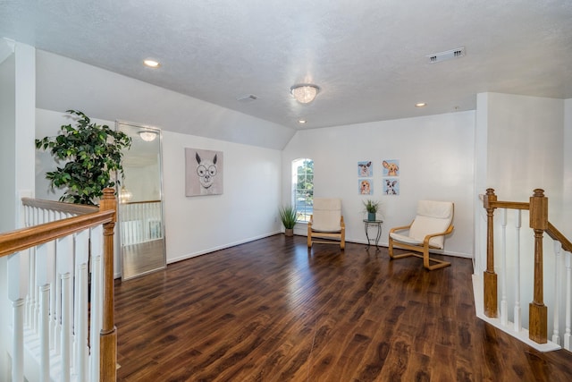living area with lofted ceiling, an upstairs landing, visible vents, and wood finished floors