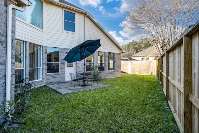 rear view of house featuring a fenced backyard, a lawn, a patio area, and brick siding