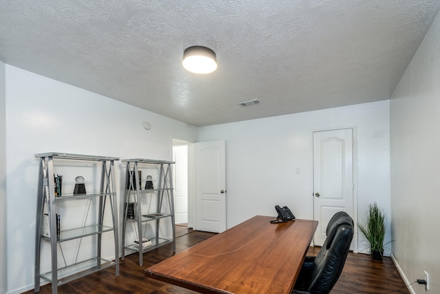office with dark wood finished floors, visible vents, and a textured ceiling