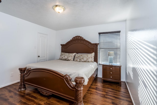 bedroom featuring a textured ceiling, baseboards, and wood finished floors