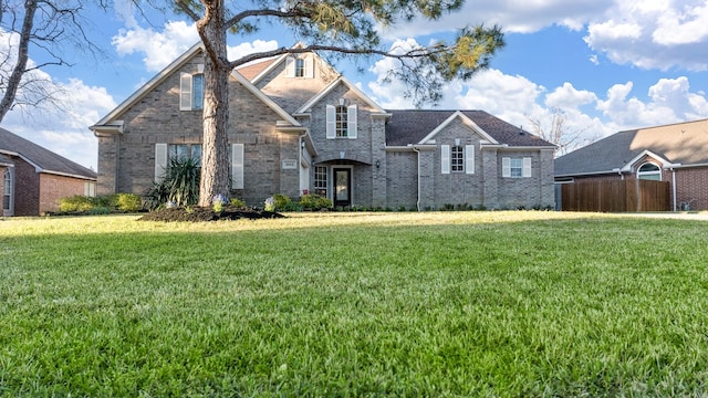 traditional-style house featuring a front lawn, fence, and brick siding