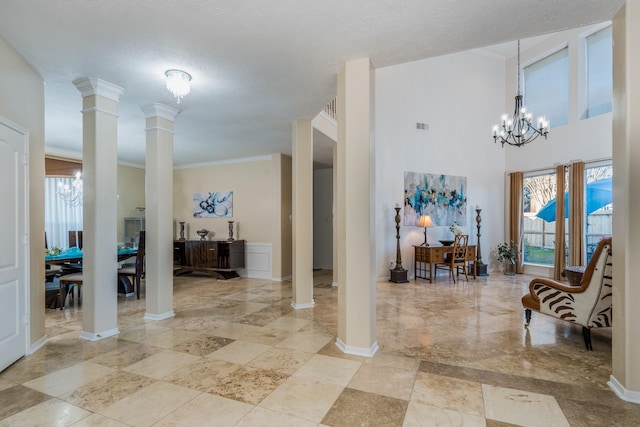 foyer with crown molding, ornate columns, baseboards, a chandelier, and visible vents