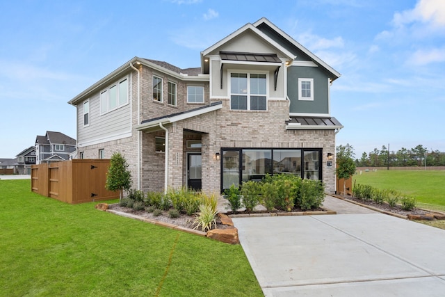 view of front of home with a standing seam roof, fence, brick siding, metal roof, and a front yard