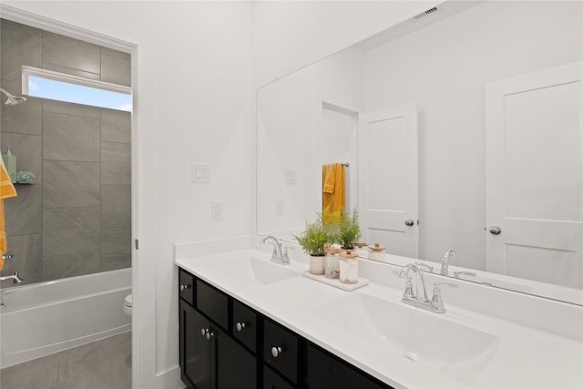 bathroom featuring toilet, double vanity, a sink, and visible vents