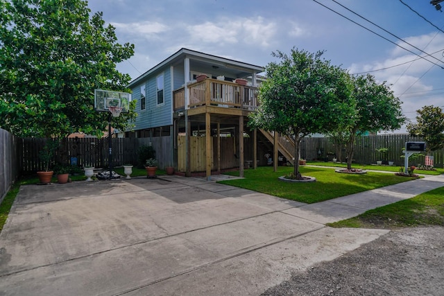view of front of house featuring a front lawn, stairs, a fenced backyard, and a deck