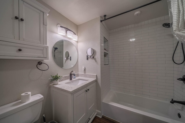 full bathroom featuring a textured wall, toilet, vanity, and shower / bathtub combination