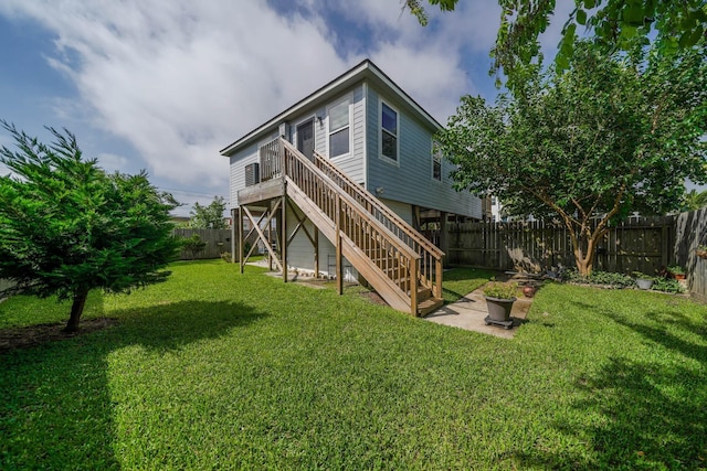 rear view of property featuring a fenced backyard, a lawn, stairs, and a deck