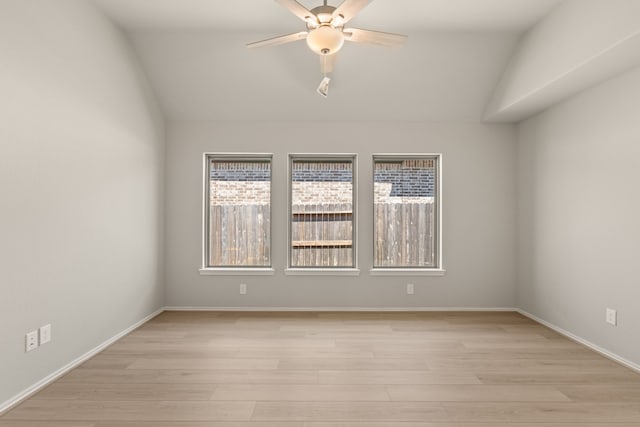 spare room with light wood-style flooring, baseboards, vaulted ceiling, and ceiling fan