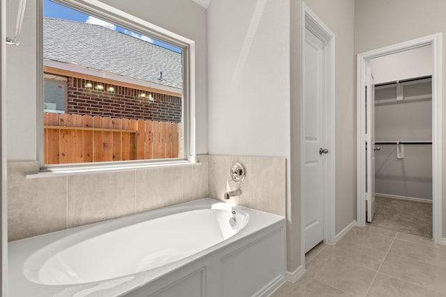full bathroom with a spacious closet, tile patterned floors, a garden tub, and a wealth of natural light