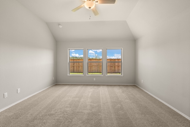 carpeted spare room featuring a ceiling fan, baseboards, and lofted ceiling