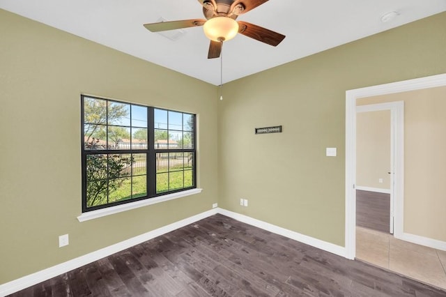 empty room with a ceiling fan, baseboards, and dark wood finished floors