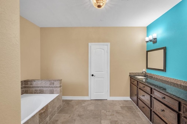 full bathroom with baseboards, tiled bath, and vanity