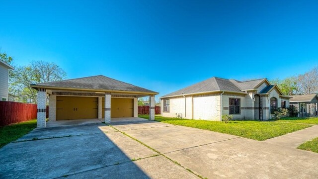 view of side of home featuring fence, a garage, concrete driveway, an outbuilding, and a yard