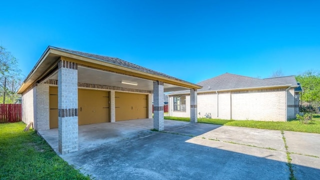 exterior space with fence, a garage, concrete driveway, brick siding, and a lawn