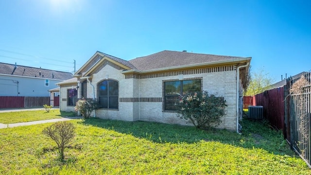view of front of house featuring central air condition unit, a front yard, fence, and brick siding