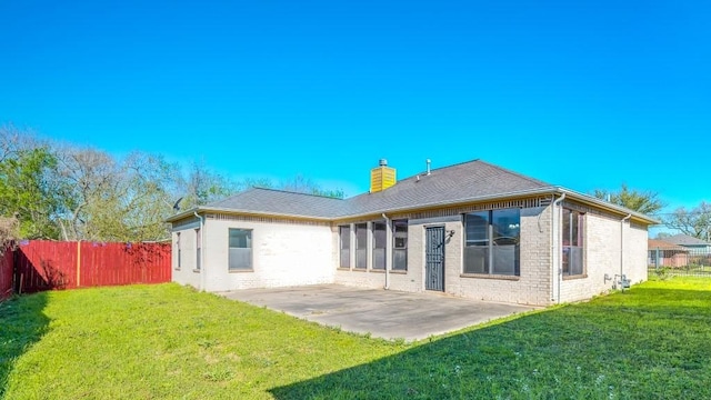 rear view of property featuring fence, a yard, and a patio area