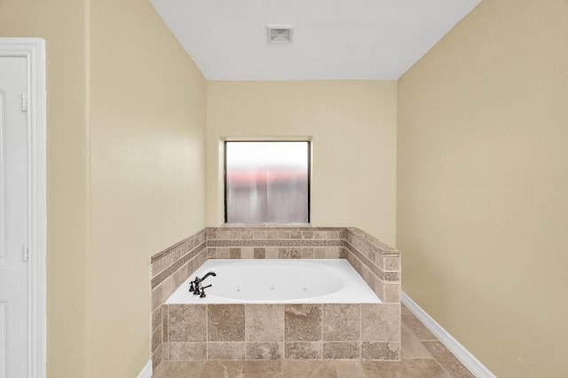 bathroom with baseboards, visible vents, and a garden tub