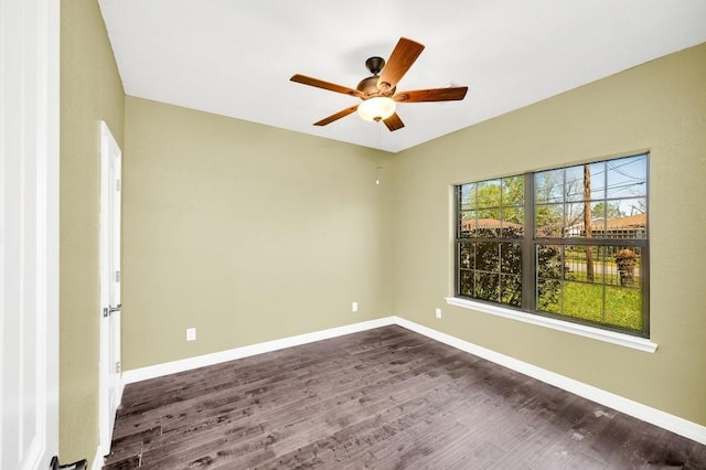 empty room with dark wood finished floors, baseboards, and a ceiling fan