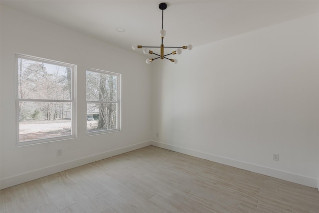 empty room featuring baseboards and a chandelier