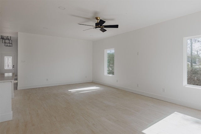 unfurnished room with a ceiling fan, baseboards, and light wood-style flooring