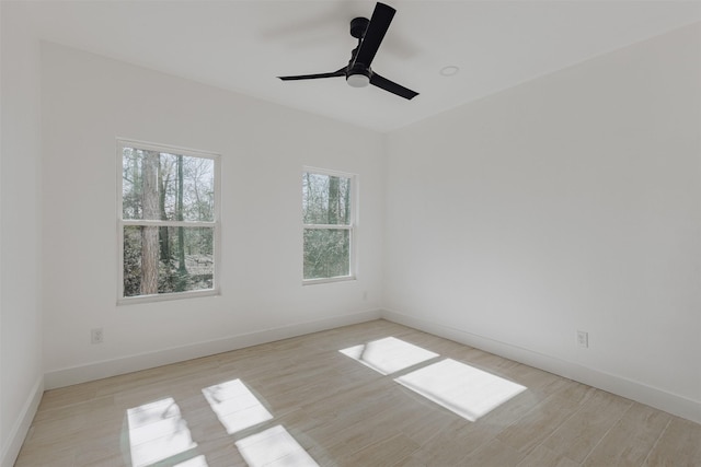 empty room featuring baseboards, ceiling fan, and light wood-style floors
