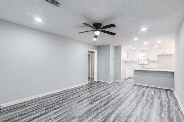 2821 1st Ave N, Texas City, TX 77590 - unfurnished living room with baseboards, visible vents, wood finished floors, and a sink