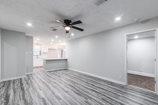 2821 1st Ave N, Texas City, TX 77590 - unfurnished living room featuring a textured ceiling, visible vents, baseboards, wood finished floors, and a ceiling fan