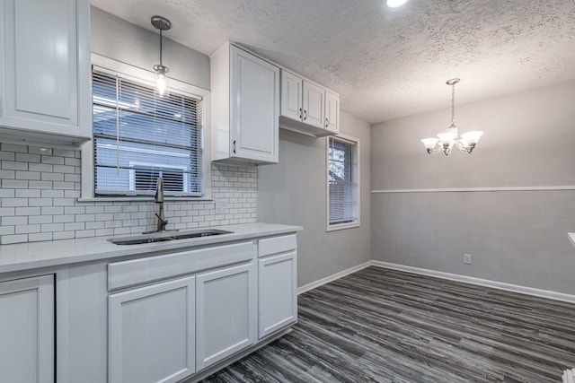 2821 1st Ave N, Texas City, TX 77590 - kitchen featuring light countertops, a sink, dark wood finished floors, white cabinets, and an inviting chandelier