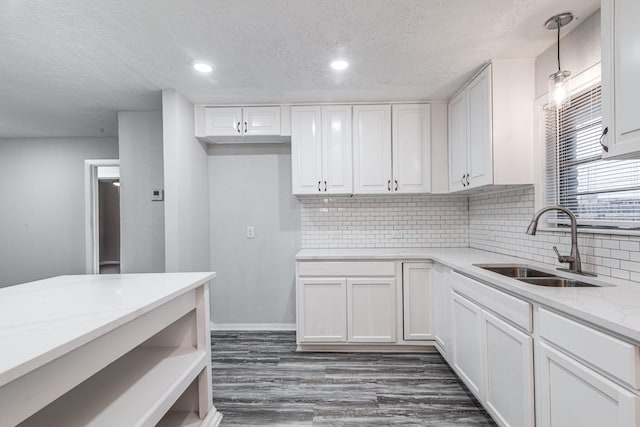 2821 1st Ave N, Texas City, TX 77590 - kitchen with light stone counters, a sink, dark wood-style floors, white cabinets, and decorative backsplash