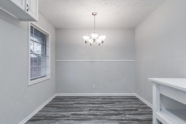 2821 1st Ave N, Texas City, TX 77590 - unfurnished dining area with dark wood-type flooring, baseboards, a chandelier, and a textured ceiling