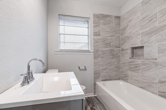 2821 1st Ave N, Texas City, TX 77590 - bathroom with toilet, vanity, wood finished floors, baseboards, and a textured wall