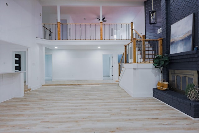 2902 Misty Park Dr, Houston, TX 77082 - unfurnished living room with a fireplace, a towering ceiling, stairway, wood finished floors, and ceiling fan