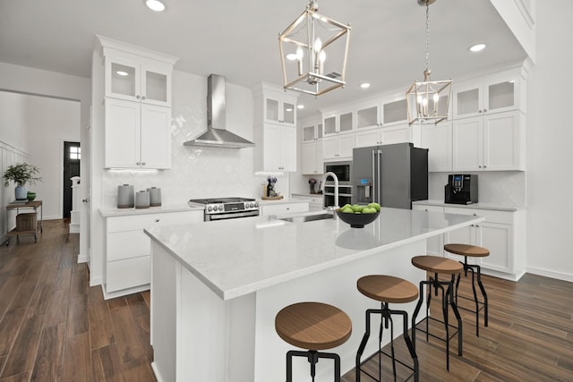 6215 Amberwood Dr, League City, TX 77573 - kitchen featuring wall chimney range hood, stainless steel appliances, recessed lighting, decorative backsplash, and a kitchen island with sink