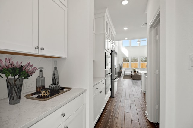 6215 Amberwood Dr, League City, TX 77573 - kitchen with oven, dark wood-style flooring, tasteful backsplash, recessed lighting, and white cabinetry