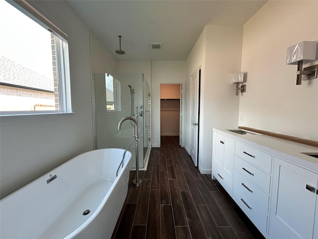 6215 Amberwood Dr, League City, TX 77573 - full bathroom featuring a shower stall, wood finished floors, a freestanding tub, a walk in closet, and double vanity