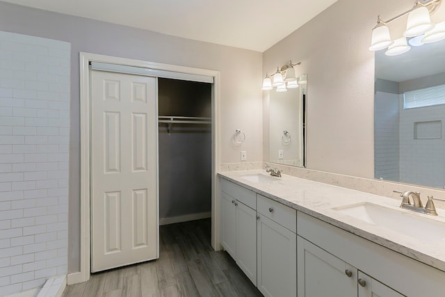 5009 Bataan Rd, Houston, TX 77033 - bathroom featuring double vanity, a sink, a walk in closet, and wood finished floors