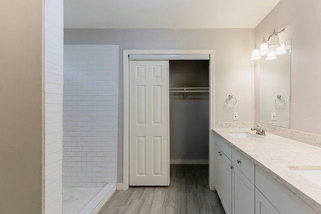5009 Bataan Rd, Houston, TX 77033 - full bath featuring a tile shower, a spacious closet, a sink, double vanity, and wood finished floors