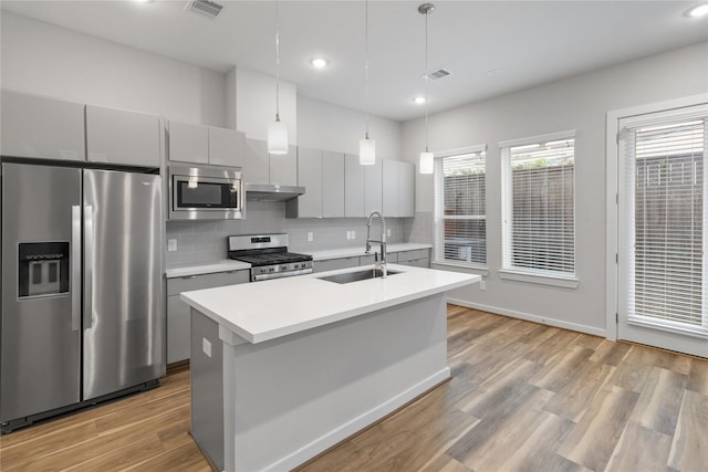 kitchen featuring a sink, gray cabinets, stainless steel appliances, backsplash, and under cabinet range hood