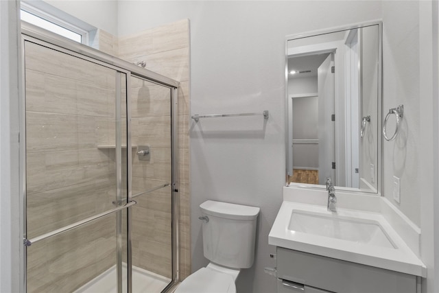 bathroom with a shower stall, toilet, and vanity