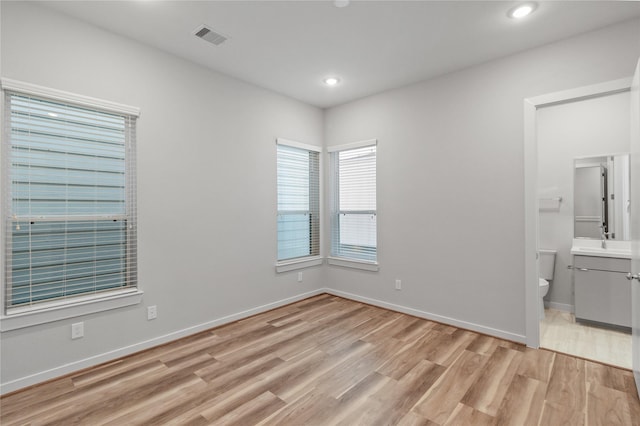 unfurnished bedroom with a sink, light wood-type flooring, baseboards, visible vents, and recessed lighting
