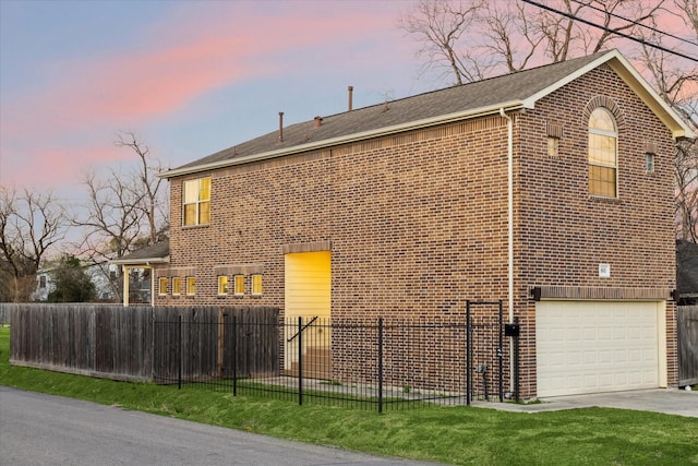 property exterior at dusk with driveway, an attached garage, fence, brick siding, and roof with shingles