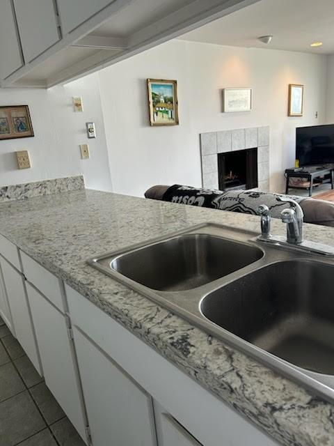 12600 Melville Dr Unit 214A, Montgomery, TX 77356 - kitchen featuring a sink, a tiled fireplace, dark tile patterned floors, and open floor plan