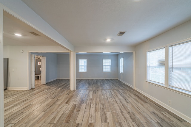 empty room with baseboards, visible vents, and light wood-type flooring