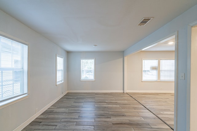 spare room featuring baseboards, visible vents, and wood finished floors