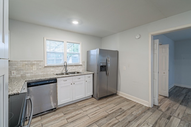 kitchen featuring a sink, white cabinetry, tasteful backsplash, light wood-type flooring, and stainless steel appliances