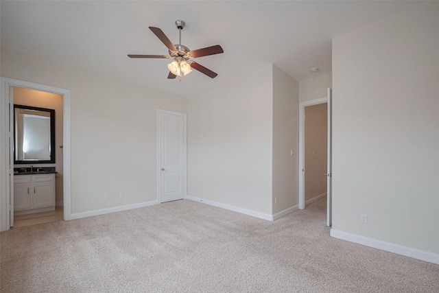 interior space with baseboards, a sink, ensuite bathroom, and light carpet